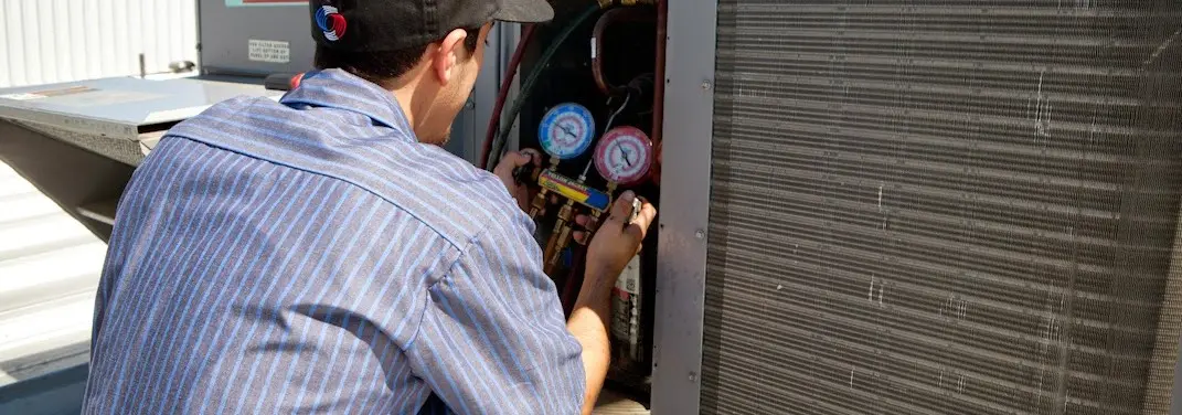 HVAC technician servicing a condenser unit in Sandwich