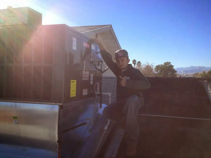 HVAC technician performing Air Duct Cleaning on a rooftop unit in Sandwich